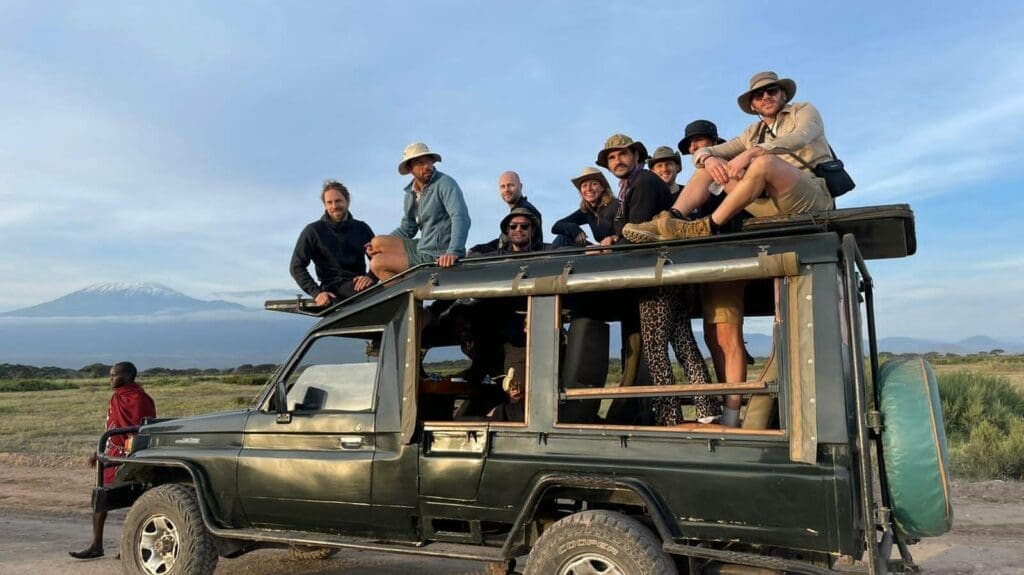groep reizigers op safari jeep met uitzicht op de besneeuwde top van de kilimanjaro