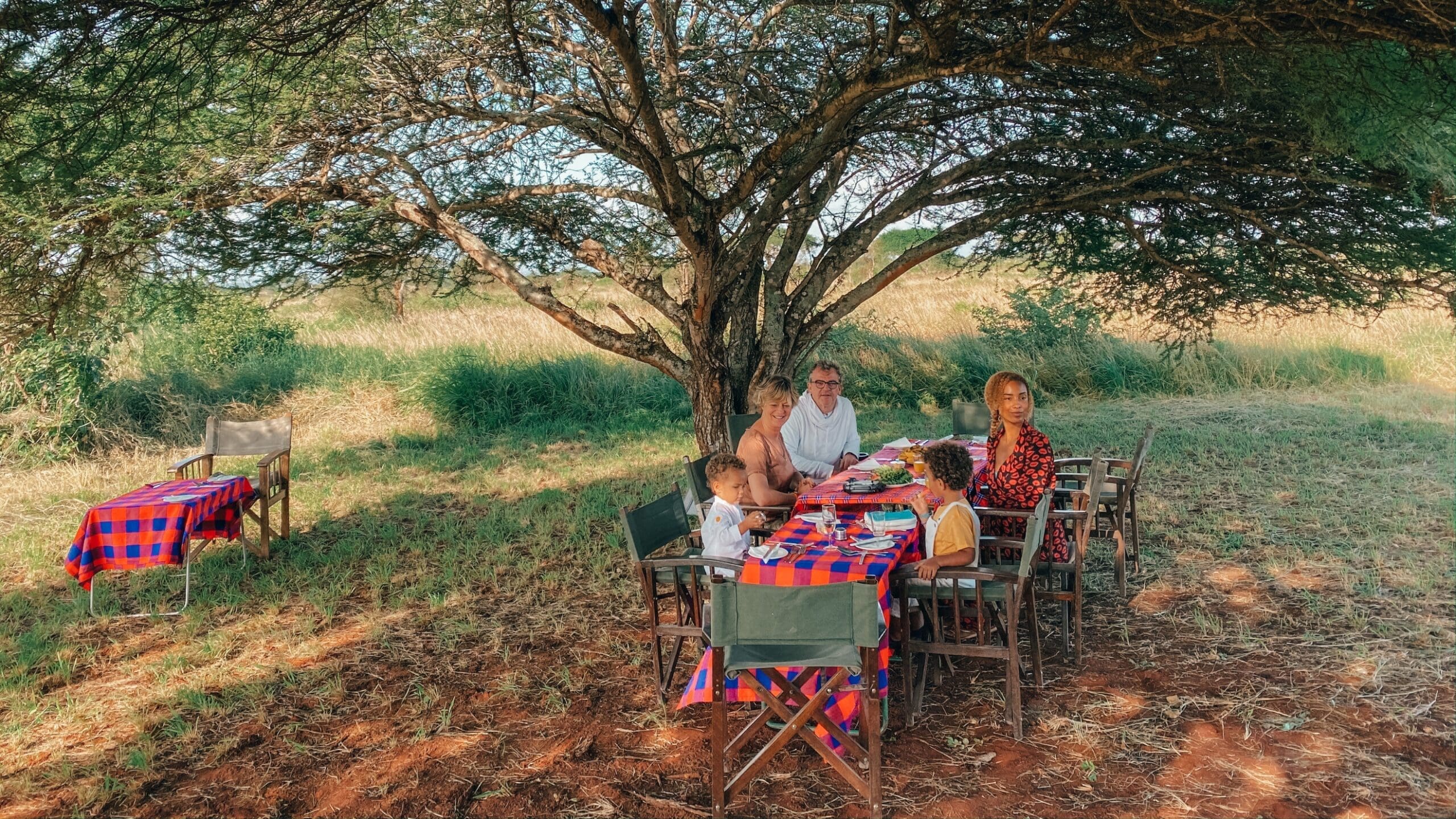 Familie ontbijt onder een grote boom midden in de Afrikaanse savanne