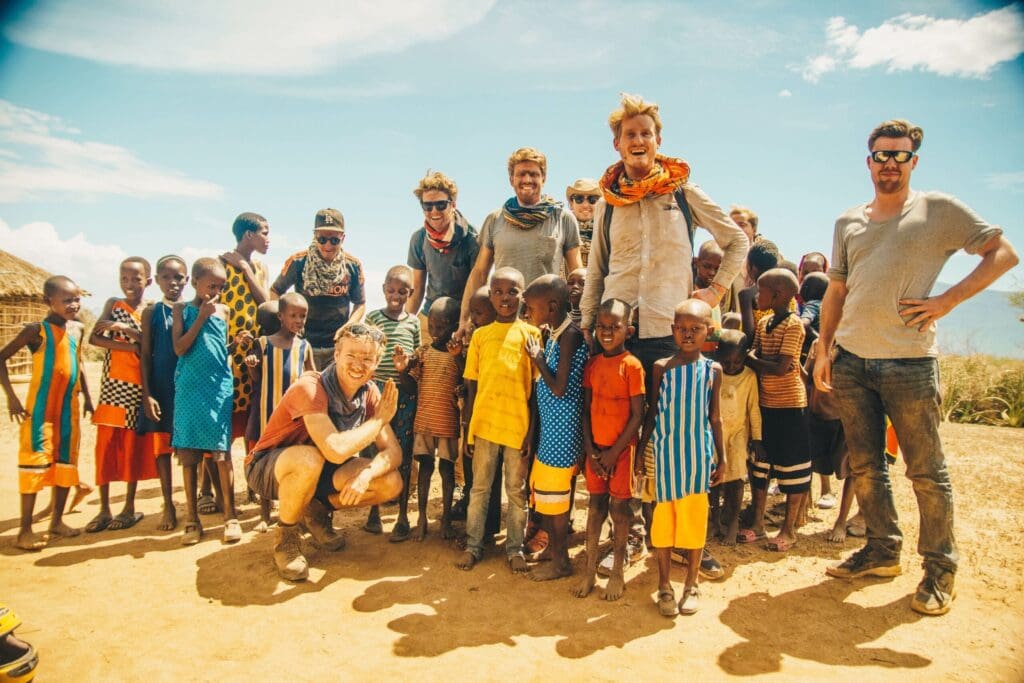 groep reizigers poseert samen met kinderen uit een lokaal dorp op een droge open plek in Kenia