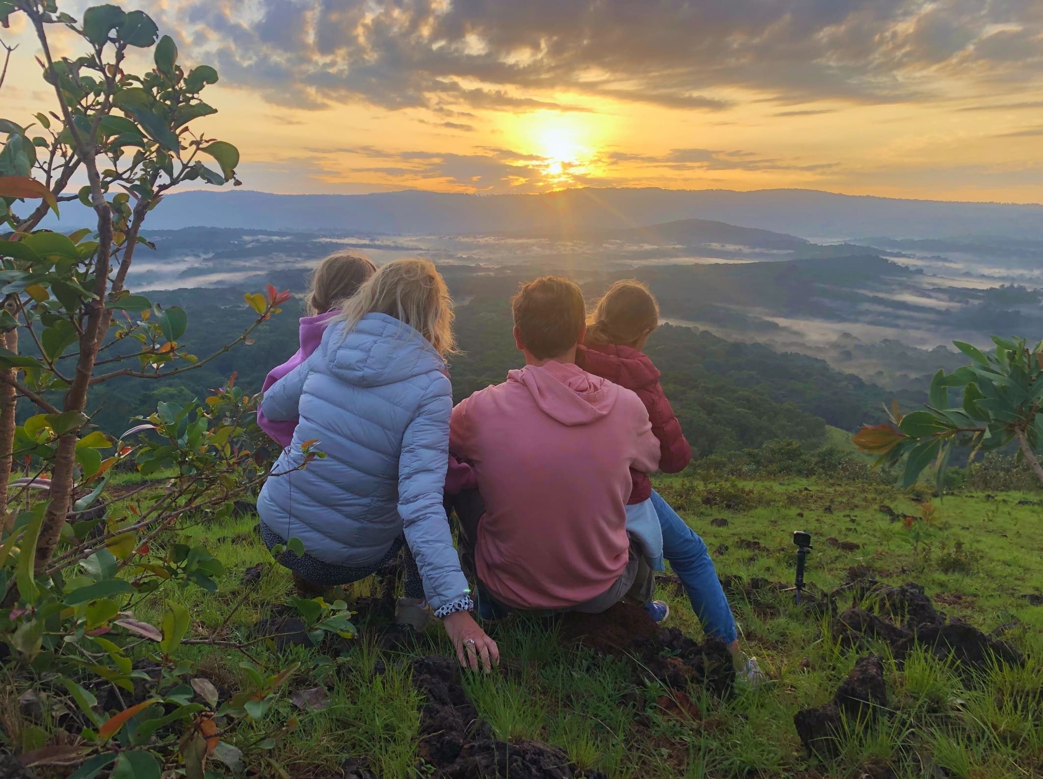 Familie geniet samen van een kleurrijke zonsopkomst boven de heuvels van Kenia