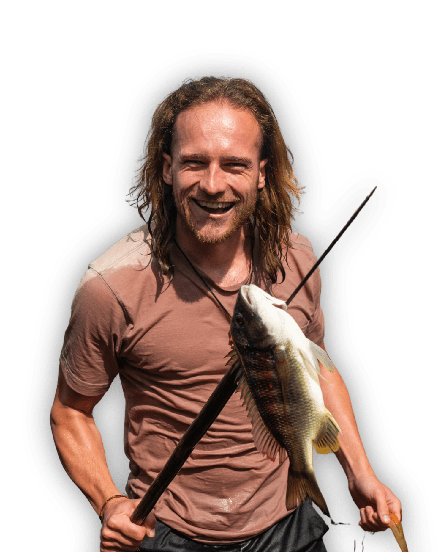 Een lachende man met lang haar houdt een grote vis aan een speer. Hij draagt een bruin t-shirt en staat tegen een effen witte achtergrond.